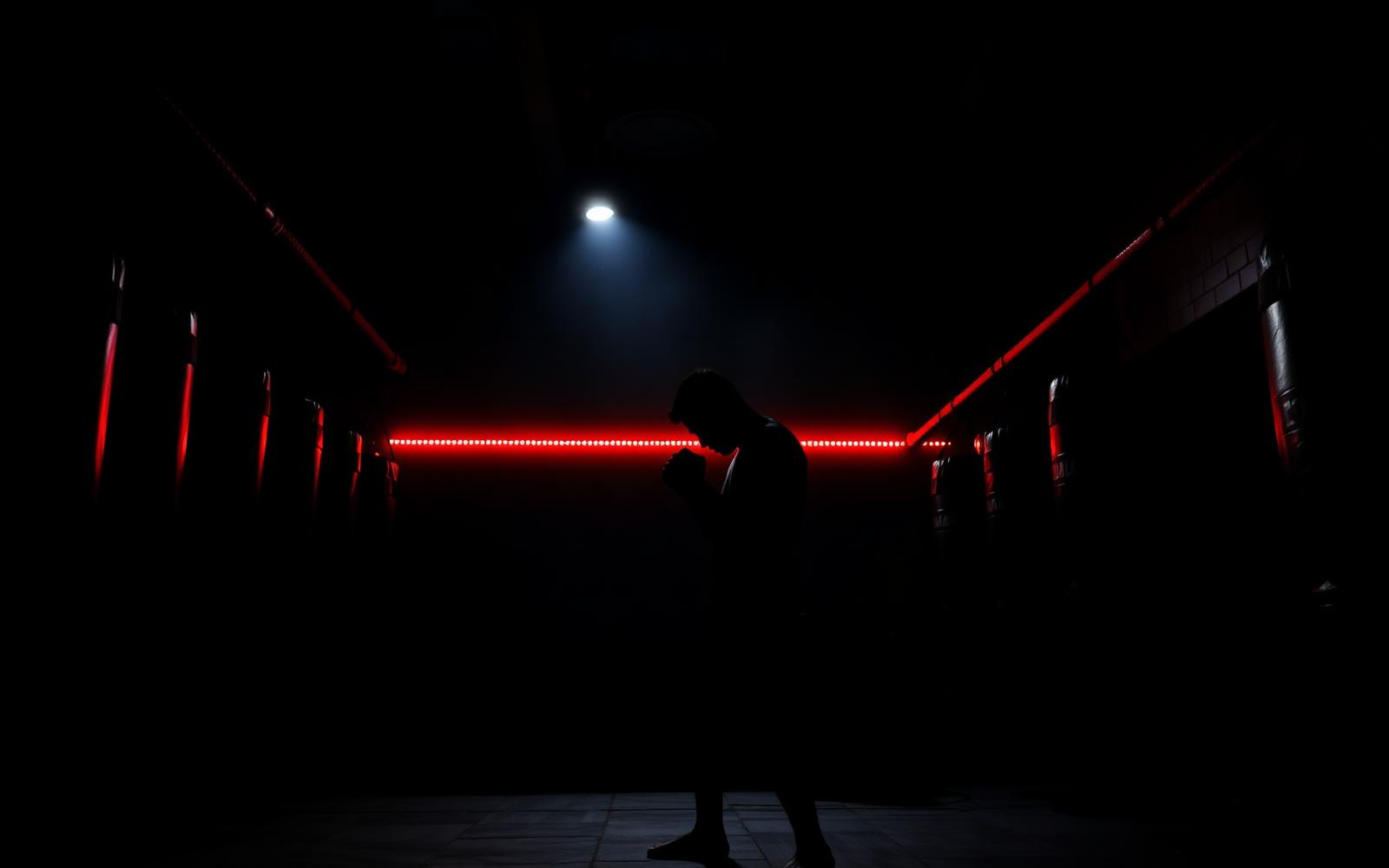 Fighter shadowboxing in a dark gym lit by red light